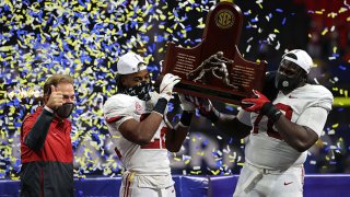 Head coach Nick Saban, Najee Harris #22, and Alex Leatherwood #70 of the Alabama Crimson Tide hold up the trophy as they celebrate their 52-46 win over the Florida Gators in the SEC Championship at Mercedes-Benz Stadium on Dec. 19, 2020 in Atlanta, Georgia.