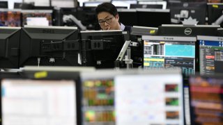 A currency dealer monitors exchange rates in a trading room at KEB Hana Bank in Seoul on March 13, 2020.