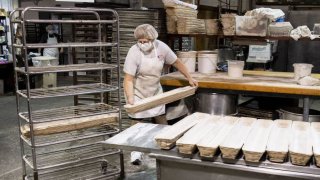 A baker places long molds of freshly kneaded sourdough dough onto racks for baking inside of Reineckers Bakery in Macedonia, Ohio, Oct. 7, 2020.