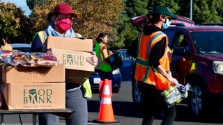 Food is loaded as drivers in their vehicles wait in line on arrival at a “Let’s Feed LA County” food distribution hosted by the Los Angeles Food Bank on December 4, 2020 in Hacienda Heights, California.