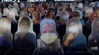 Cutout photos of people, including first responders and healthcare workers, sit in seats in Gillette Stadium