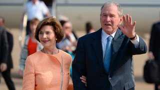 Former US President George W. Bush (R) waves to journalists next to his wife Laura (L) as they arrive for an official visit to Botswana, in Gaborone on April 4, 2017.