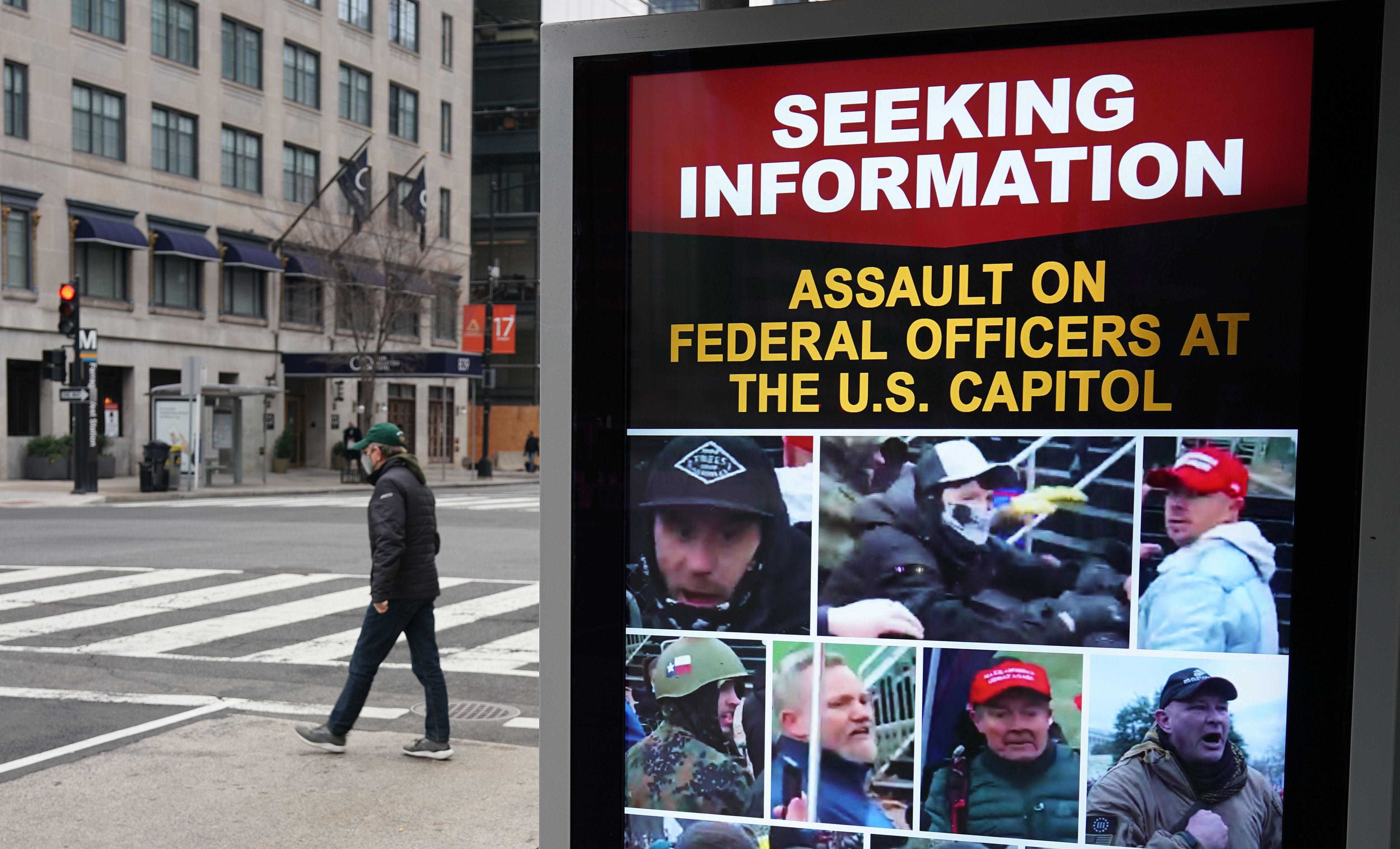 A monitor at a bus shelter near the White House shows images of people wanted in connection with the insurrection at the US Capitol in Washington, DC on January 14, 2021. (Photo by MANDEL NGAN / AFP)