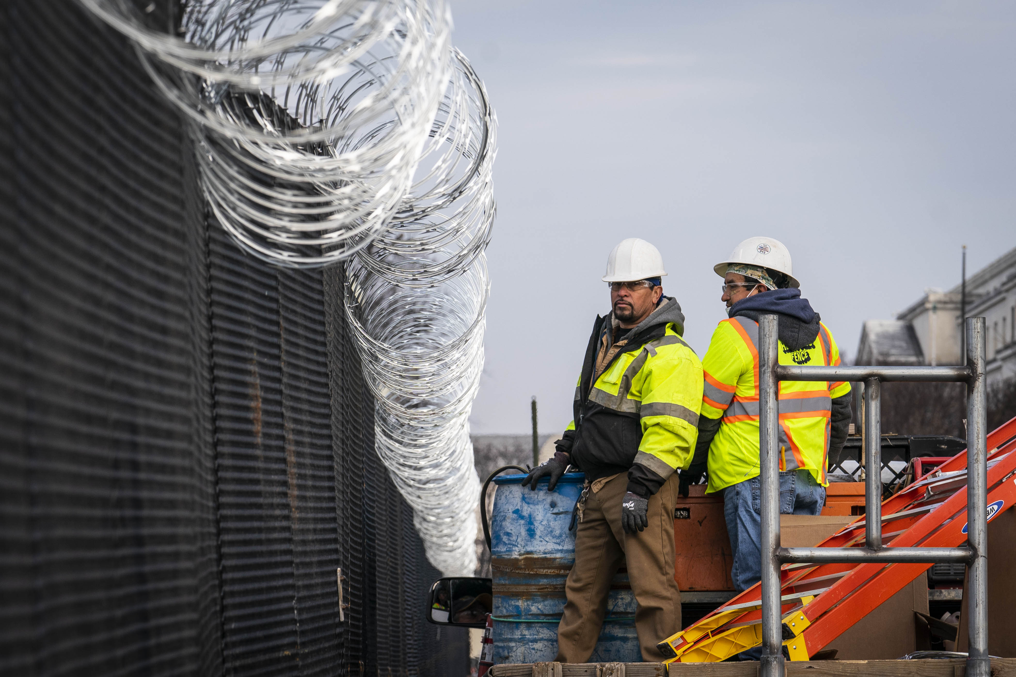Workers install barbed wire on the fenced perimeter of the U.S. Capitol in Washington, D.C., U.S., on Friday, Jan. 15, 2021. The timing for both President Trump&#8217;s impeachment trial and legislation to provide Americans with more Covid relief now largely depends on maneuvering by three of the most veteran legislative tacticians in Congress. Photographer: Sarah Silbiger/Bloomberg via Getty Images