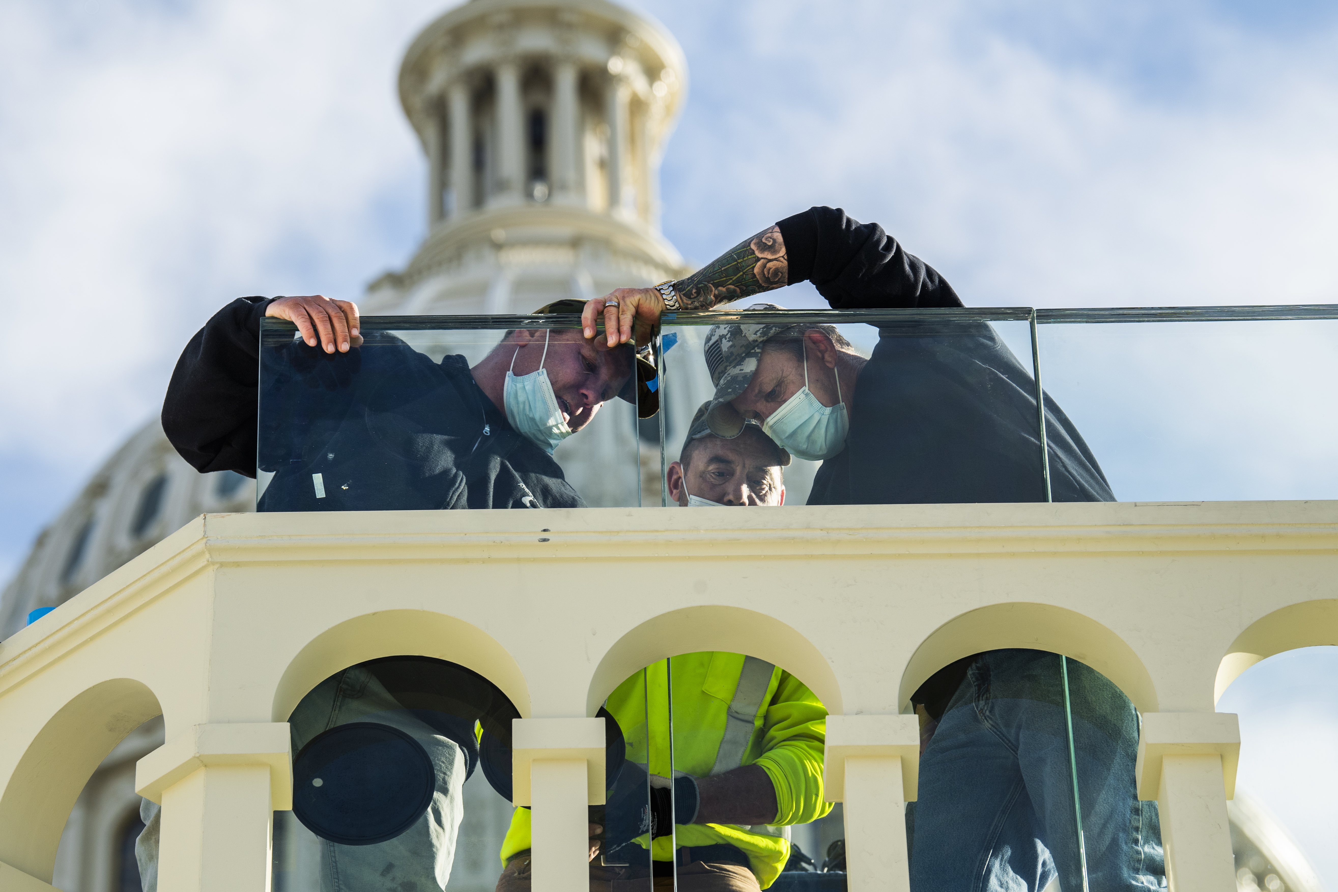UNITED STATES &#8211; JANUARY 13: Workers install heavy glass around the podium where President-elect Joe Biden will be sworn in, during preparations for the inauguration on the West Front of the Capitol on Wednesday, January 13, 2021. (Photo By Tom Williams/CQ-Roll Call, Inc via Getty Images)