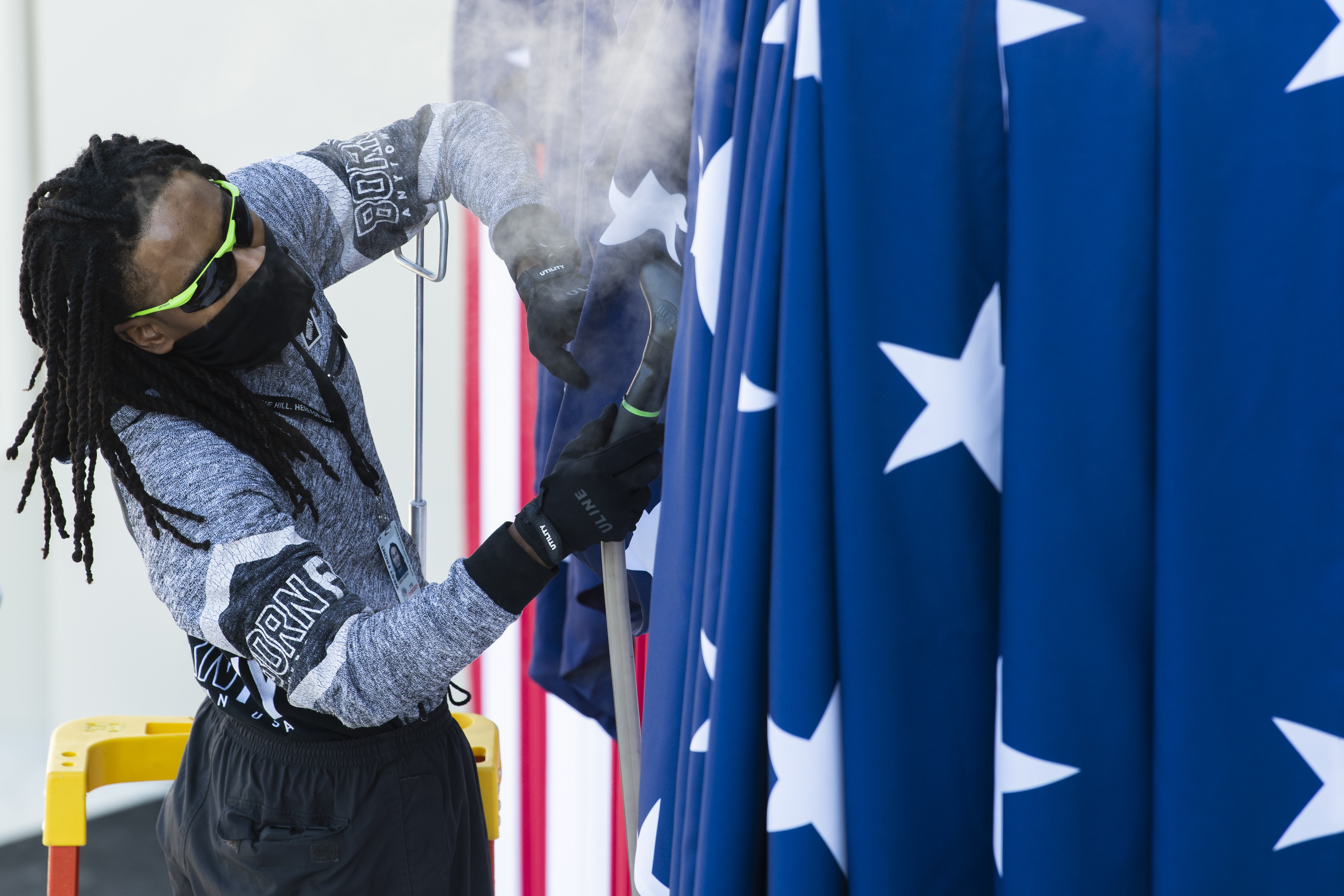 UNITED STATES &#8211; JANUARY 13: A worker steams an American flag bunting under the podium where President-elect Joe Biden will be sworn in, during preparations for the inauguration on the West Front of the Capitol on Wednesday, January 13, 2021. (Photo By Tom Williams/CQ-Roll Call, Inc via Getty Images)