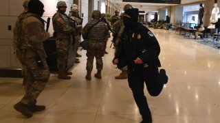 Members of the US National Guard leave the US Capitol to take positions outside as a member of the Capitol police runs by, after an “external security threat” prior to a dress rehearsal for the 59th inaugural ceremony for President-elect Joe Biden and Vice President-elect Kamala Harris, at the US Capitol on January 18, 2021 in Washington, DC. – The Inauguration is scheduled for January 20, 2021. (Photo by ANDREW CABALLERO-REYNOLDS / AFP)