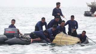In this Jan. 10, 2021, file photo, Indonesian Navy divers pull out a part of an airplane out of the water during a search operation for the Sriwijaya Air passenger jet that crashed into the sea near Jakarta, Indonesia.