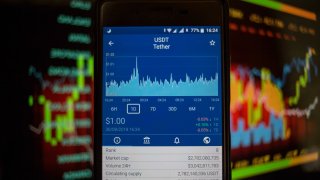A smartphone displays the Tether market value on the via The Crypto App.