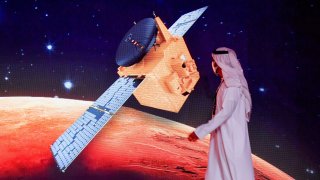 An Emirati walks past a screen displaying the “Hope” Mars probe at the Mohammed Bin Rashid Space Centre in Dubai on July 19, 2020.