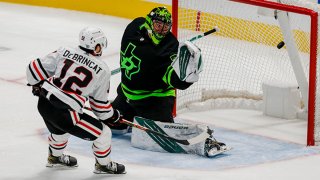 Chicago Blackhawks left wing Alex DeBrincat (12) scores a goal against Dallas Stars goaltender Jake Oettinger (29) in overtime to win the game between the Dallas Stars and the Chicago Blackhawks on Feb. 7, 2021 at American Airlines Center in Dallas, Texas.