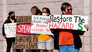 Supermarket workers hold placards in protest in front of a Food 4 Less supermarket in Long Beach, California on February 3, 2021, after a decision by owner Kroger to close two supermarkets rather than pay workers an additional $4.00 in “hazard pay” for their continued work during the coronavirus pandemic. – Kroger, which owns Ralphs and Food 4 Less, said it will close one of each store in April after the Long Beach city council passed a law mandating “hazard pay” for grocery store workers. Long Beach was the first city in the region to approve a hazard pay ordinance.