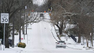 Vehicles travel on a snow-covered road in McKinney, Texas, Feb. 16, 2021.