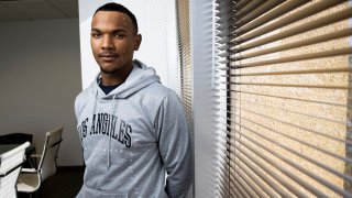 Damon Mathias standing next to a window in a grey hoodie that says Los Angeles