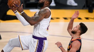 LOS ANGELES, CALIFORNIA - FEBRUARY 28: LeBron James #23 of the Los Angeles Lakers scores on a layup past Stephen Curry #30 of the Golden State Warriors during the second quarter at Staples Center on February 28, 2021 in Los Angeles, California.
