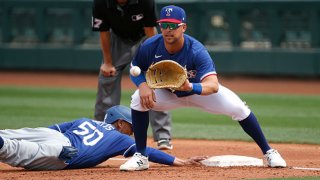 First baseman Nate Lowe #30 of the Texas Rangers fields a throw on a pick-off attempt of base runner Mookie Betts #50 of the Los Angeles Dodgers in the fourth inning of the MLB spring training baseball game at Surprise Stadium on March 7, 2021 in Surprise, Arizona.