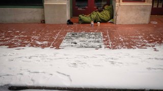 With temperatures already falling into the single digits homeless person sleeps in the doorway of the Majestic Theater as a winter storm brings snow and freezing temperatures to North Texas on Sunday, Feb. 14, 2021, in Dallas.