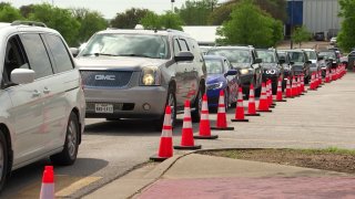 People line up for drive-through COVID-19 vaccinations at the Ellis Davis Field House in Dallas, April 7, 2021.