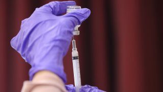 In this March 25, 2021, file photo, nurses draw vaccine doses from a vial as Maryland residents receive their second dose of the Moderna coronavirus vaccine at the Cameron Grove Community Center in Bowie, Maryland.