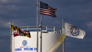 Flags fly in front of a Colonial Pipeline Co. storage tank at a facility in the Port of Baltimore in Baltimore, Maryland, U.S., on Tuesday, May 11, 2021.