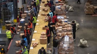 Workers from Chinese e-commerce giant JD.com prepare parcels for delivery at the company’s main logistics hub for Singles Day on November 11, 2020 in Beijing, China.