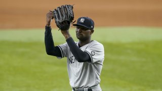 New York Yankees starting pitcher Domingo German taps his glove as he walks to the dugout after working against the Texas Rangers in the seventh inning of a baseball game in Arlington, Texas, Thursday, May 20, 2021.