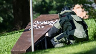 A bomb squad member investigates the coffin that was placed on Dallas County District Attorney John Creuzot's front lawn May 29, 2021.