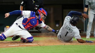 Jonah Heim #28 of the Texas Rangers stretches to make the tag on Kyle Lewis #1 of the Seattle Mariners for the final out of the game at Globe Life Field on May 8, 2021 in Arlington, Texas.