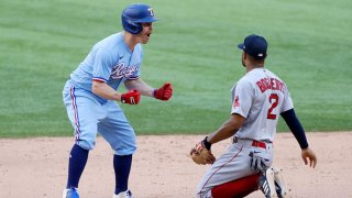 Brock Holt #16 of the Texas Rangers reacts after hitting a two-run go ahead double as Xander Bogaerts #2 of the Boston Red Sox looks away during the eighth inning at Globe Life Field on May 2, 2021 in Arlington, Texas.