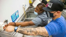 Payton Ceasar, 17, shows "dish-washing guy" how to use the sink before he starts his shift as a volunteer dishwasher at Café Momentum, which employs teens coming out of juvenile detention in Dallas County.