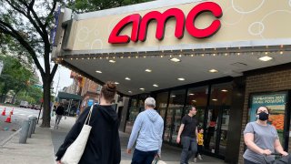 Pedestrians pass in front of an AMC theater in New York.