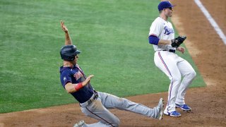 Max Kepler #26 of the Minnesota Twins scores on a wild pitch as John King #60 of the Texas Rangers looks on during the seventh inning at Globe Life Field on June 19, 2021 in Arlington, Texas.