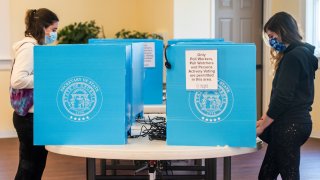 FILE - In this Jan. 5, 2021, file photo, Emily Murdock, left, and her twin sister Elizabeth Murdock vote in Georgia's U.S. Senate runoff election in Evans, Ga. A federal judge on Wednesday, July 7, 2021, declined to block some challenged sections of Georgia's new election law ahead of two runoff elections scheduled for next week, but he didn't rule out the possibility for future elections.