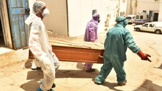 Tunisian municipality employees seen carrying a casket of a COVID-19 victim at the regional hospital during the coronavirus infections.