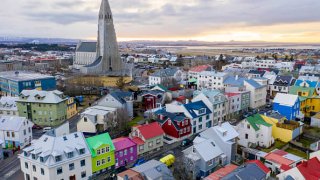 Wide landscape views of buildings, cars, people, homes, apartments, mountains, streets, water, and businesses are seen in Reykjavik, Iceland on December 18, 2018.