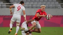 Britain's Ben Harris, right, is tackled by Martin Iosefo of the United States as Steve Tomasin of the United States pursues, in their men's rugby sevens quarterfinal match at the 2020 Summer Olympics, Tuesday, July 27, 2021 in Tokyo, Japan.