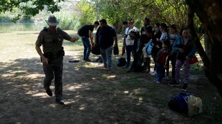 Texas Department of Public Safety officers work with a group of migrants who crossed the border and turned themselves in Del Rio, Texas