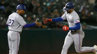 Joey Gallo #13 of the Texas Rangers celebrates with third base coach Tony Beasley #27 after hitting a solo home run in the top of the ninth inning against the Oakland Athletics at RingCentral Coliseum on June 30, 2021 in Oakland, California.