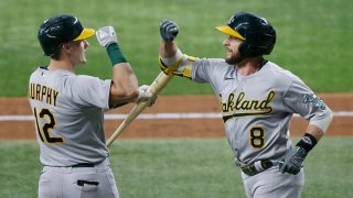 Jed Lowrie #8 of the Oakland Athletics celebrates with teammate Sean Murphy #12 after Lowrie hit a solo home run against the Texas Rangers during the fourth inning at Globe Life Field on July 10, 2021 in Arlington, Texas.