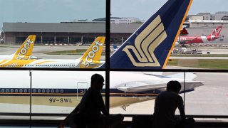 A Singapore Airlines plane is parked beside Scoots passenger planes on the terminal tarmac at Changi International Airport in Singapore on March 15, 2021.