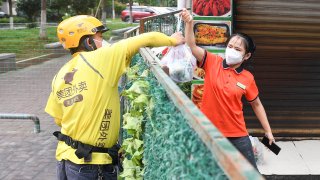 A Meituan food courier delivers a bag of food to a resident of a neighborhood under lockdown due to the recent COVID-19 outbreak on August 11, 2021, in Zhangjiajie, Hunan Province of China.