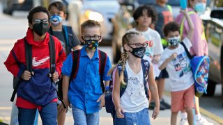 In this Tuesday, Aug. 10, 2021 file photo, Students, some wearing protective masks, arrive for the first day of school