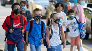 In this Tuesday, Aug. 10, 2021 file photo, Students, some wearing protective masks, arrive for the first day of school