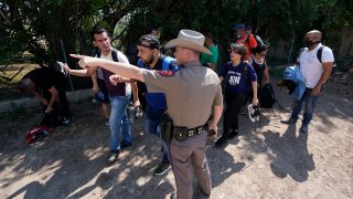 In this Wednesday, June 16, 2021, file photo, A Texas Department of Public Safety officer in Del Rio, Texas directs a group of migrants who crossed the border and turned themselves in.