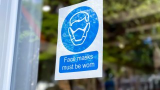 covid-19 mask required sign posted on retail store door