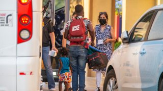 Volunteers with Faith Forward Dallas help migrant families from Haiti and Cuba exit a coach bus at a hotel in Irving, Wednesday, August 11, 2021.