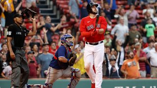 As catcher Jose Trevino #23 of the Texas Rangers and umpire Jeremie Rehak #35 look on, Travis Shaw #23 of the Boston Red Sox watches his game winning grand slam home run during the 11th inning at Fenway Park on Aug. 23, 2021 in Boston, Massachusetts.