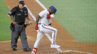 Adolis Garcia #53 of the Texas Rangers touches home plate as umpire Marvin Hudson #51 looks on, after hitting a two-run home run against the Houston Astros during the third inning at Globe Life Field on Sept. 14, 2021 in Arlington, Texas.