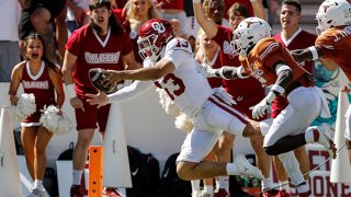 Caleb Williams #13 of the Oklahoma Sooners dives for a touchdown in the first half defended by D'Shawn Jamison #5 of the Texas Longhorns during the 2021 AT&T Red River Showdown at Cotton Bowl on Oct., 2021 in Dallas, Texas.