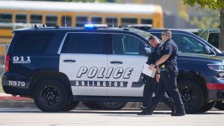 Law enforcement officers walk in the parking lot of Timberview High School after a shooting inside the school located in south Arlington, Texas, Oct. 6, 2021.